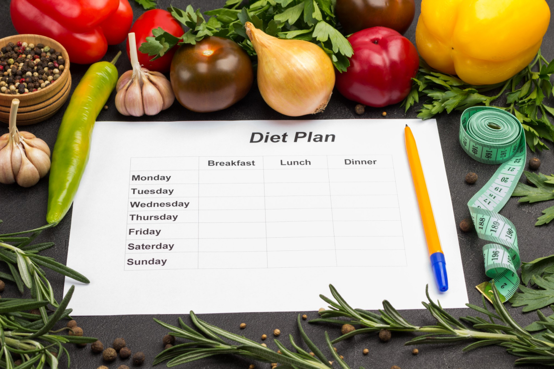 A diet plan sheet surrounded by fresh vegetables, symbolizing a healthy reset.