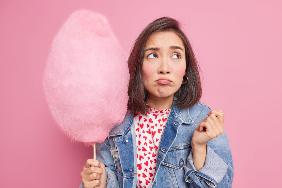 Fluffy pink cotton candy on a stick, symbolizing a sugary, low-nutrient treat.